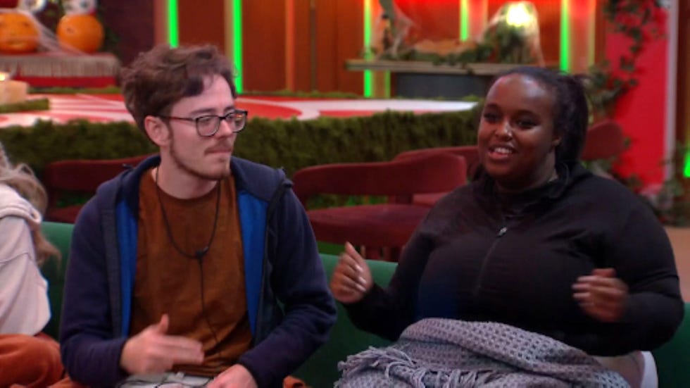 big brother samuel yasmin two people sitting on a sofa, smiling and gesturing.