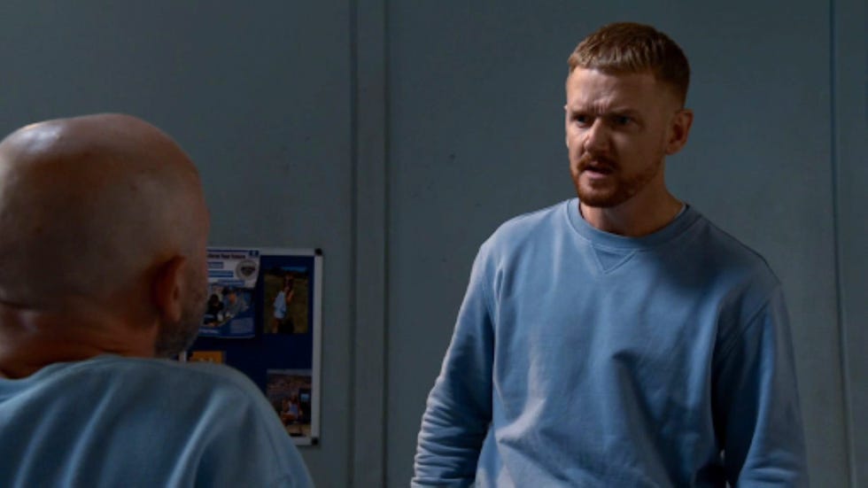 coronation street gary windass two men in blue sweatshirts having a tense conversation in a room.