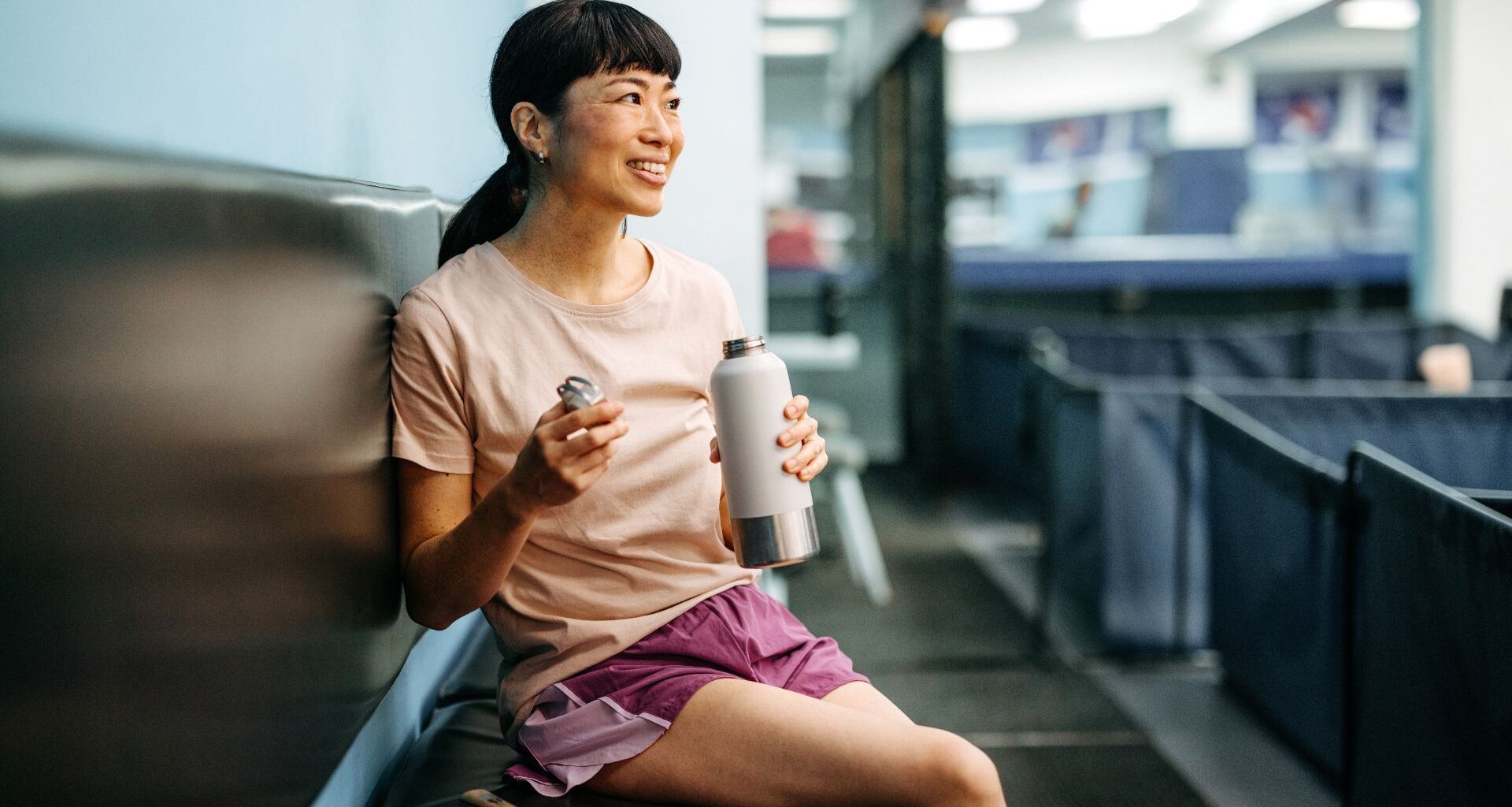 Woman drinking from water bottle at gym