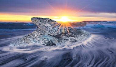Big icy rock in the sea with a sunset background