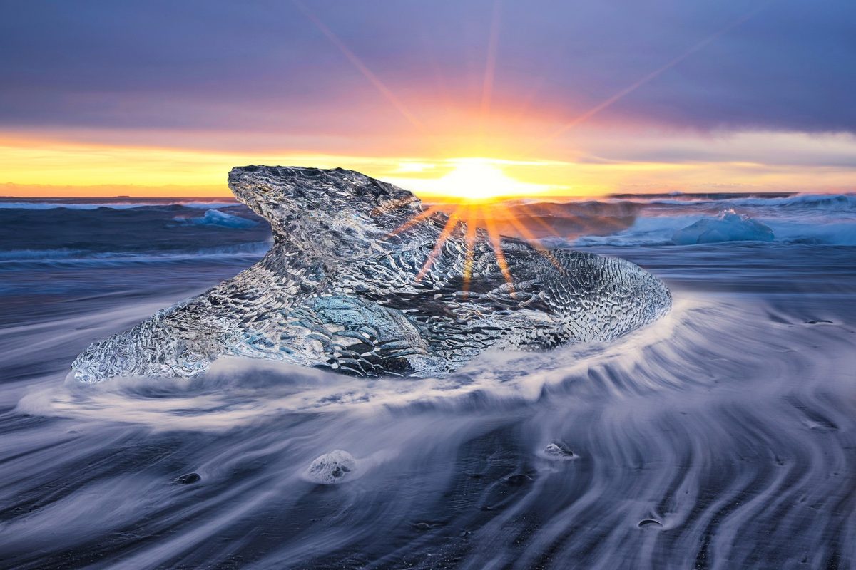 Big icy rock in the sea with a sunset background