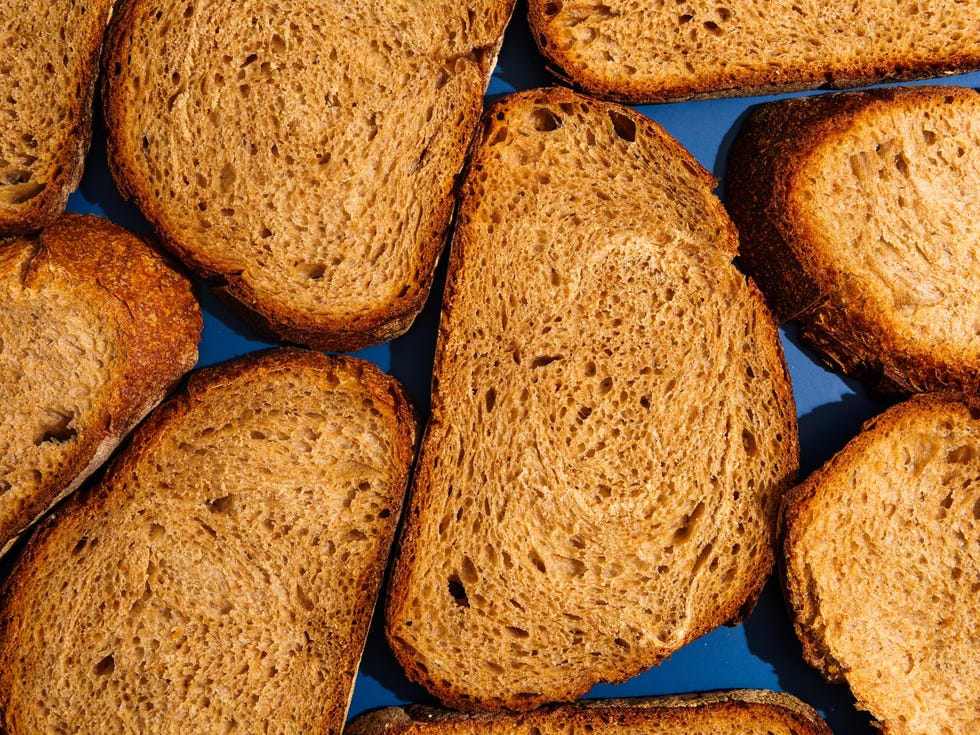 Slices of whole wheat bread on blue background slices of fresh whole wheat bread organized on a vibrant blue background, creating a minimalist food texture