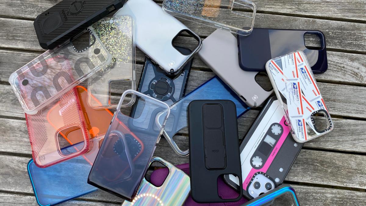 A pile of iPhone 12 cases of various styles rests on a wooden surface.