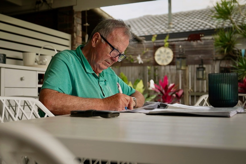 an older man looks at some bills and paperwork