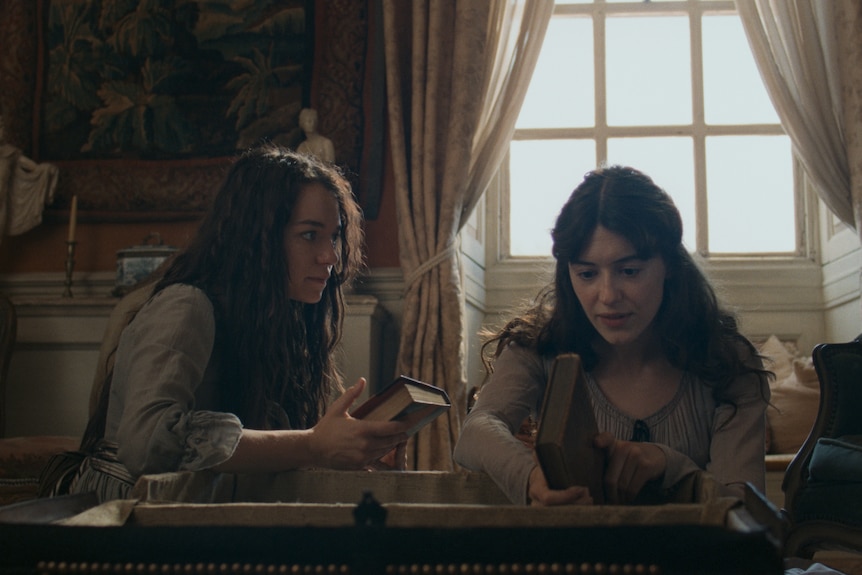 Two young women look over some books in a trunk