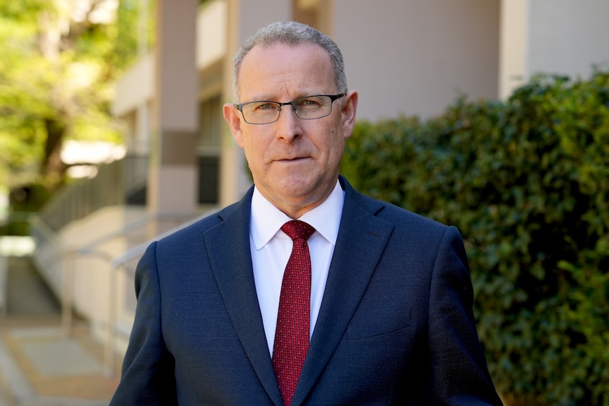 man with grey hair and glasses in a suit