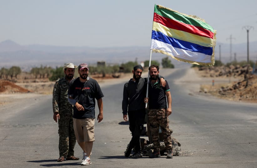 People hold a Druze flag, following deadly clashes between Druze fighters, Sunni Bedouin tribes, and government forces, in Syria's predominantly Druze city of Sweida, Syria July 25, 2025.