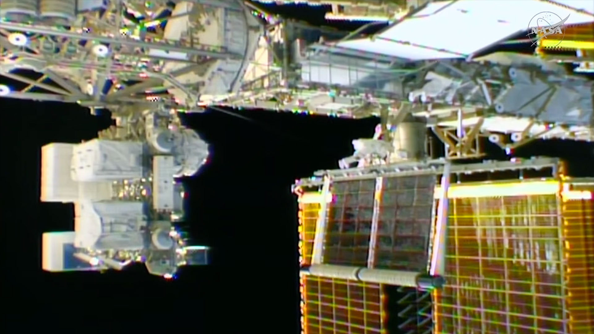 a rolled-up solar array is seen unfurling outside of a space station