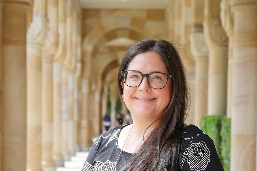 A professional headshot of Stacey Parker taken among sandstone archways at the University of Sydney.