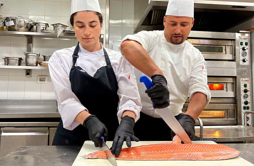 Team members at the Waldorf Astoria Jerusalem kitchen cut a salmon to prepare it for the breakfast buffet.