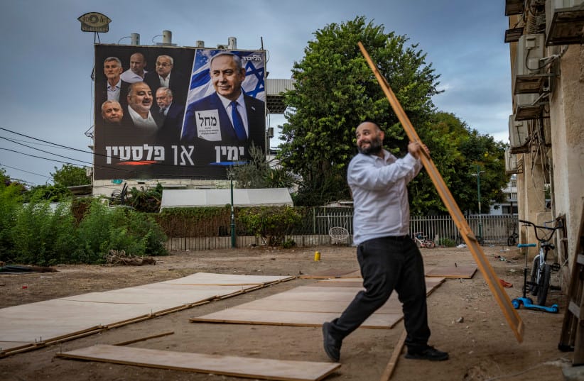 Israelis dismantle their sukkahs next to a Likud election campaign poster featuring Prime Minister Benjamin Netanyahu alongside opposition leaders and the slogan “Right or Palestine,” in the southern Israeli city of Ashdod, October 5, 2026