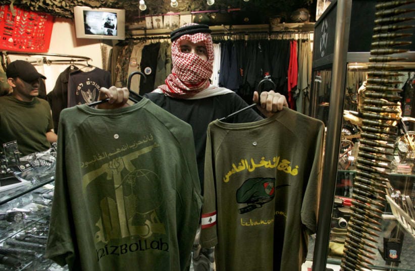 A shop assistant, who refused to be identified, displays T-shirts presenting the official logotype of radical Islamic Shiite group Hezbollah (L) and another of Lebanese Army´s special forces (R), on sale at an army and navy police supply shop, in Sao Paulo, Brazil, July 28, 2006.