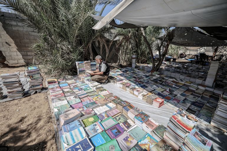 Mohammed Saad sorts through and organises books inside a tent in Deir al-Balah, Gaza.