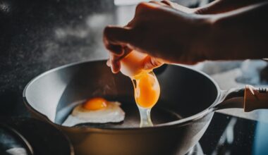 Close-up of female hand cracking an egg into a sizzling hot frying pan