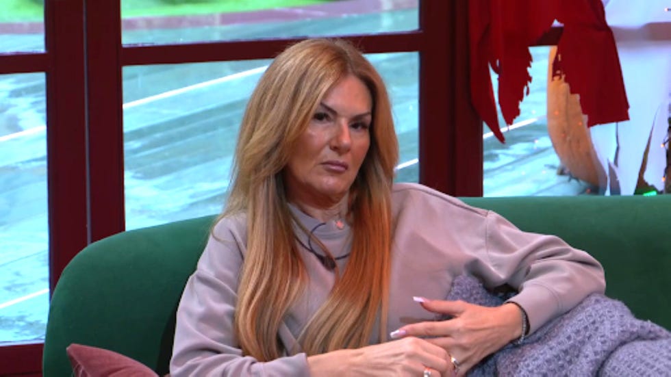 big brother rochelle woman with long hair sitting on a green couch indoors.