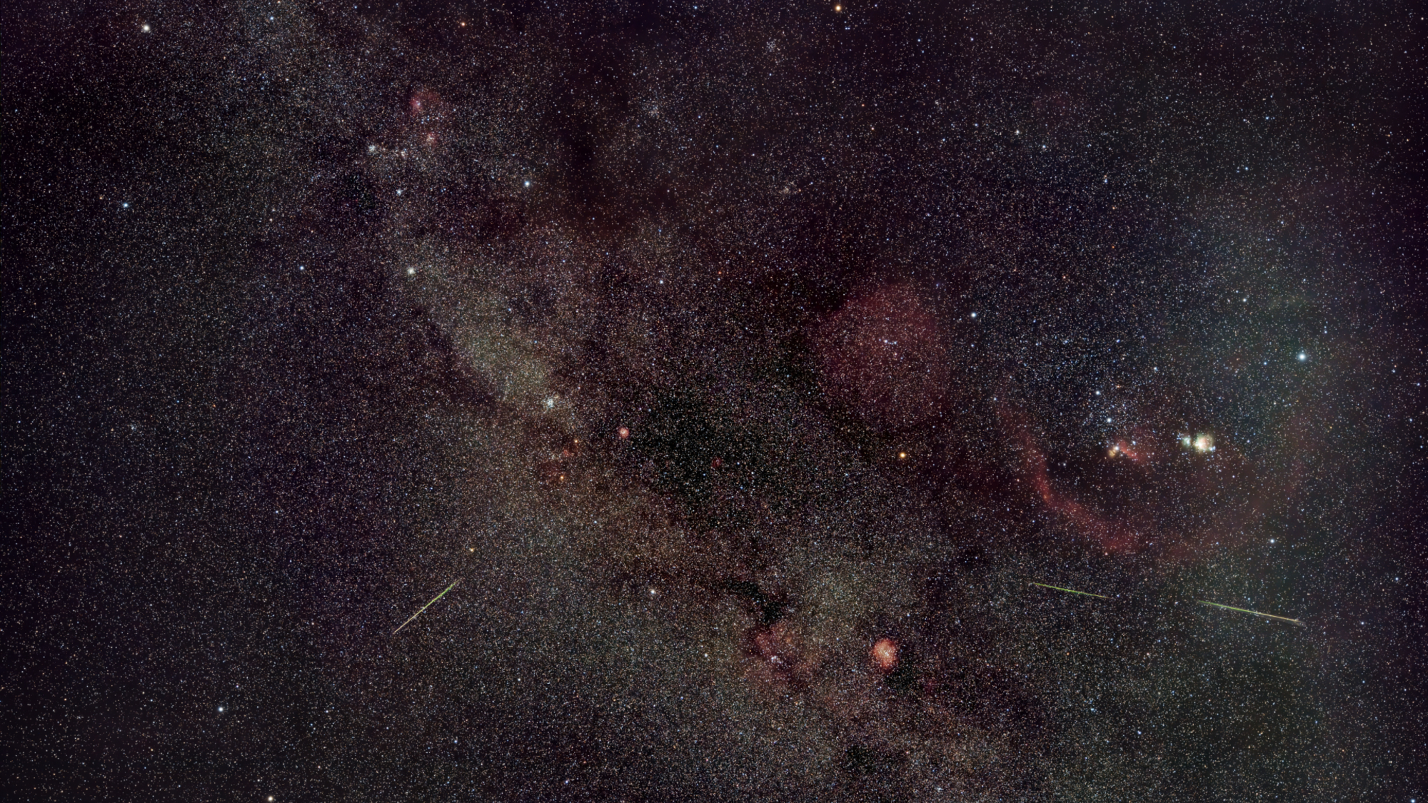A photo of meteors streaking through a starry sky dotted with glowing nebulas and star clusters.