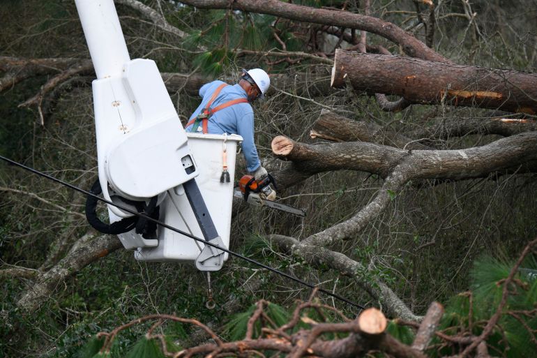 Florida Power & Light worker Yosvany Quintero clears downed tree limbs caused by the effects of Isaias on Saturday, Oct. 10, 2026, in East Milton, Fla. (AP Photo/Octavio Jones)