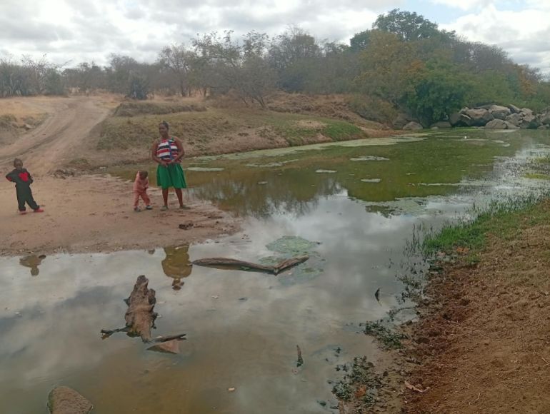 Agnes Handidikundiona, a resident of a platinum-mining community in Zimbabwe, stands at the Ngwazani River in Turf with her children