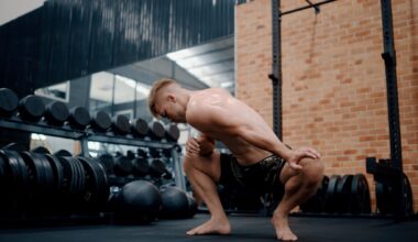 Athletic male in shorts at the gym performing a low squat hold while stretching out his hips