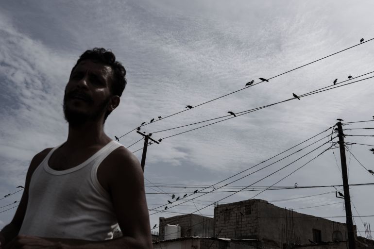 A man walks beneath a web of power lines in a neighborhood in Aden, Yemen. Long and frequent electricity cuts have become part of daily life for residents across the city. Photo: Belal Khaled