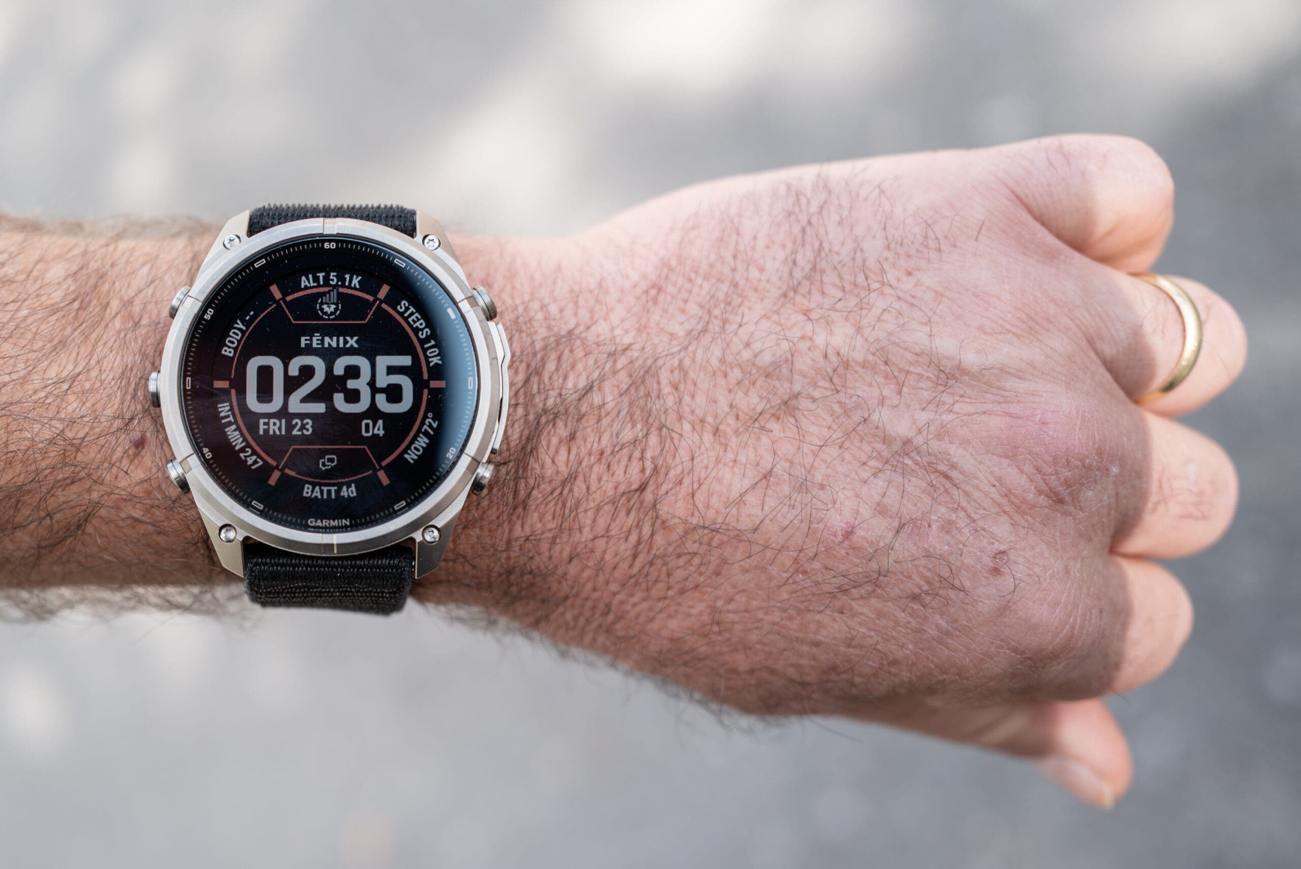Garmin fenix 9 Pro watch with a silver titanium bezel and black nylon strap on a hairy wrist, its black watch face showing the time 02:35, altitude, steps and battery data.