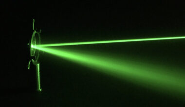 a green laser beam reflected off a piece of optical equipment.
