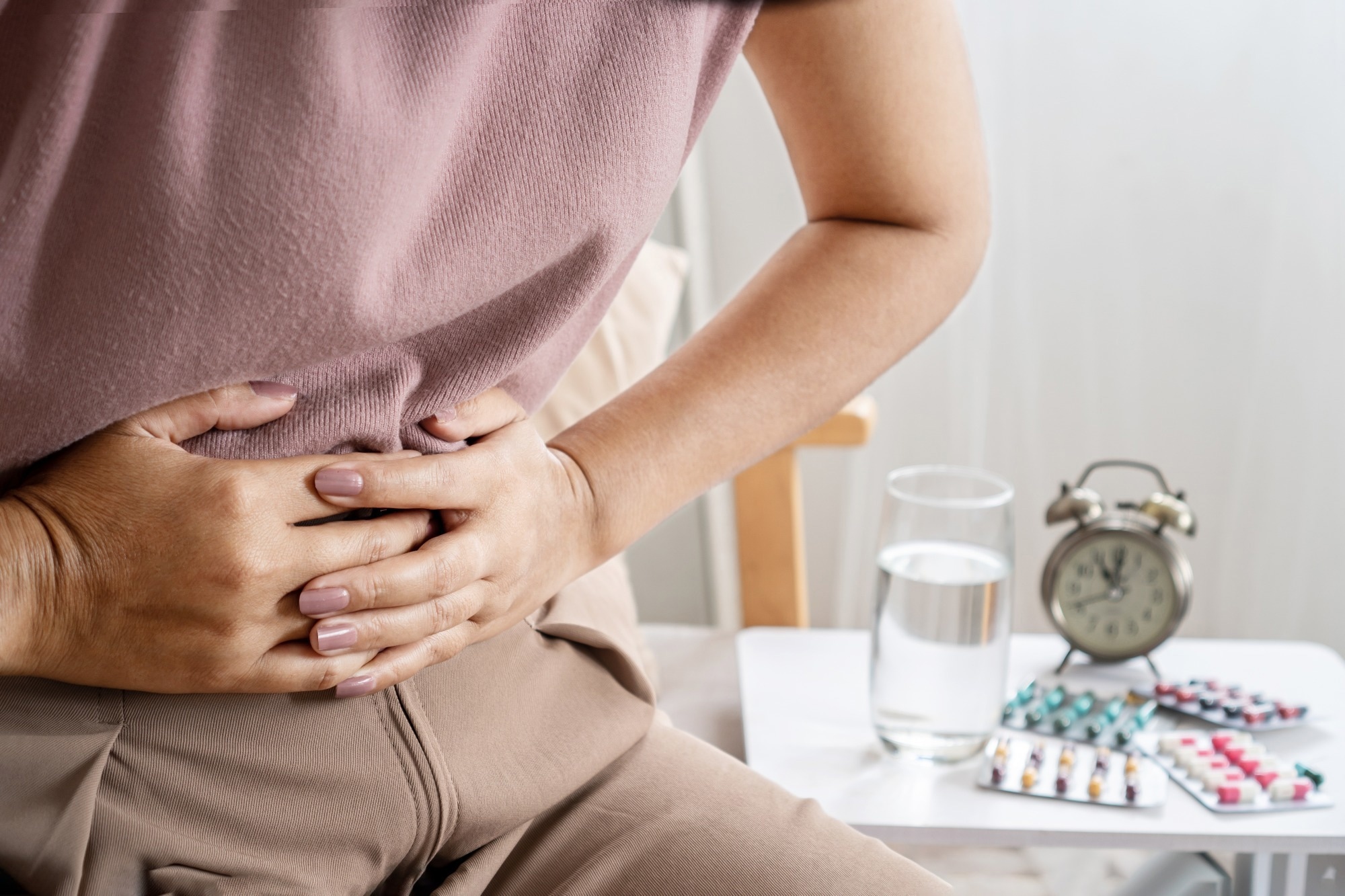 Woman hunched over holding abdomen in pain