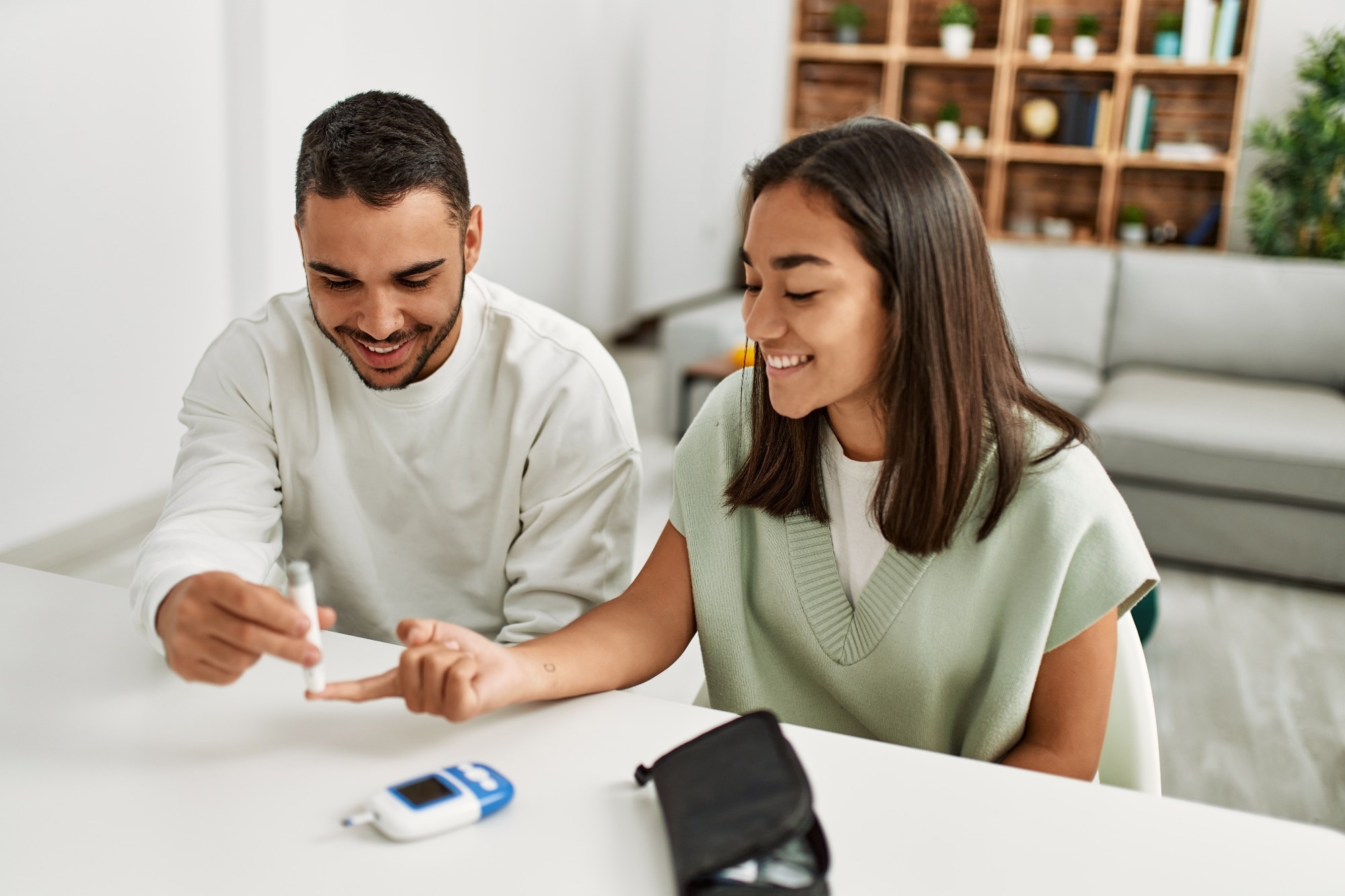 Young couple smiling happy measuring glucose at home.