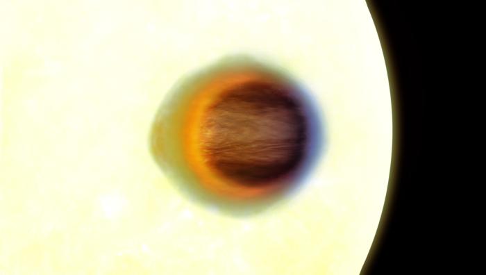 WASP-17b transiting in front of its star revealing the shape of its absorbing atmosphere through JWST observations. The hot extended red side is gas transported from the permanently irradiated dayside across the evening limb of the planet, the cooler blue side is less extended as the gas has cooled across the nightside of the planet and it is being transported across the morning limb. This technique can be used to measure the changing weather patters around the planet resolving the shape of the planet as a function of angle around the transmitting limb. Credit Engine House and Hannah Wakeford