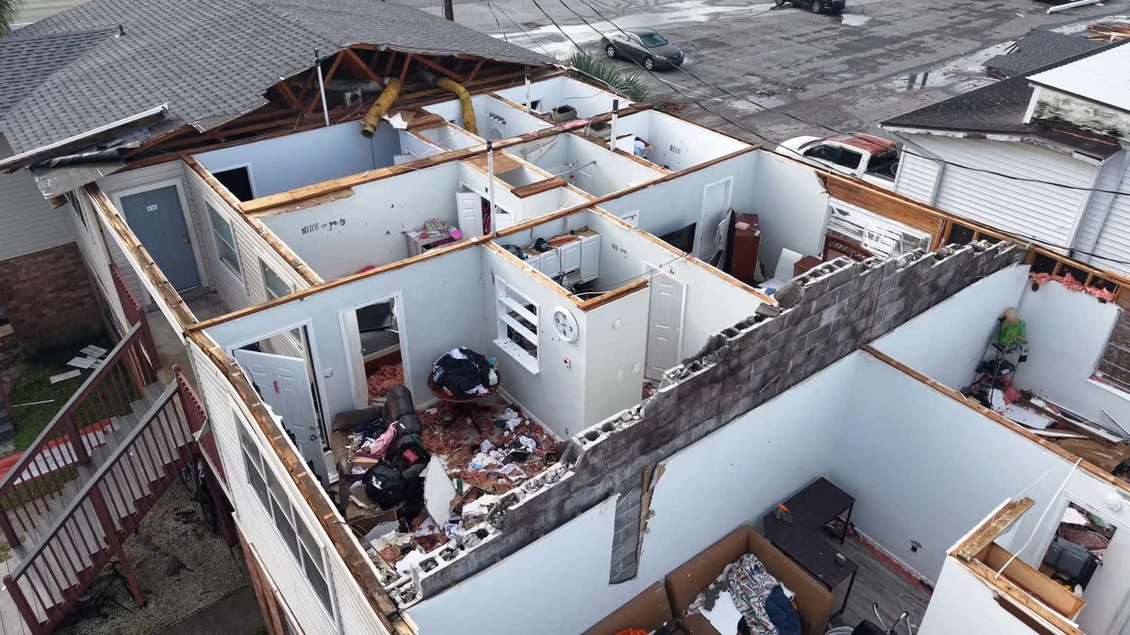 Root of apartment building ripped off with debris and damage surrounding 