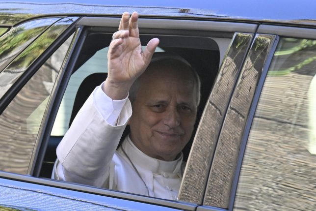 Pope Leo XIV waves from the window of the car as he leaves the Vatican before being admitted to Rome's Gemelli University Hospital for an operation to remove a lump from his lung, in the Vatican on 13 October 2026. (Photo by Tiziana FABI / AFP via Getty Images)