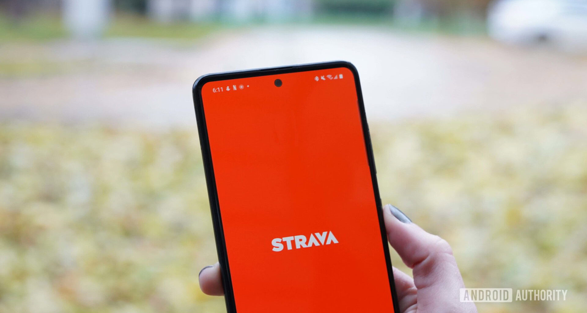 The Strava fitness app home screen is displayed on a Samsung Galaxy A51 on a leaf strewn street.