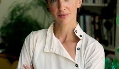 Portrait of Sandra Terdjman in a white button-down shirt, arms folded, against a softly blurred background.