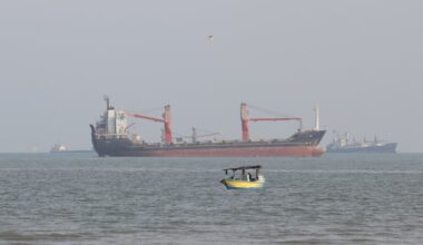 A boat floats as commercial vessels appear anchored in the Strait of Hormuz off Bandar Abbas, Iran, Tuesday, Oct. 13, 2026. Attacks on ships in the strait escalated sharply in the last week.