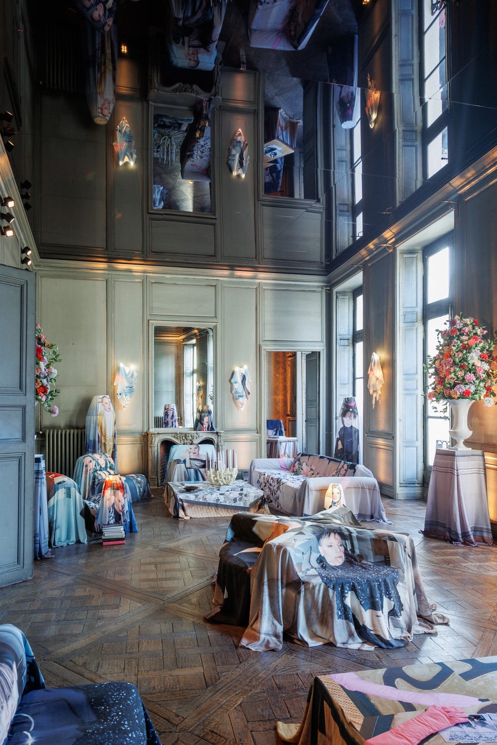 Artistic room with creatively draped fabrics, mirrors, and floral arrangements reflecting a contemporary aesthetic.