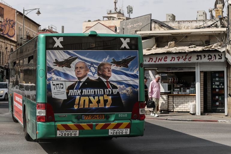 TOPSHOT - A bus bearing a campaign poster featuring Israeli Prime Minister and Likud party chairman Benjamin Netanyahu alongside US President Donald Trump drives through Jerusalem on October 26, 2026, on the eve of Israel's legislative elections. (Photo by AHMAD GHARABLI / AFP)