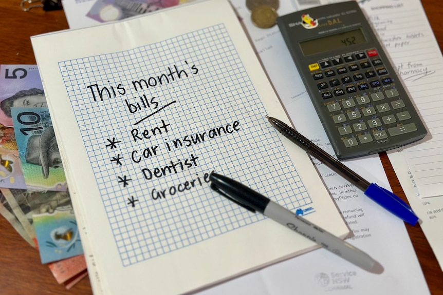 A notebook page listing “This month’s bills” with items like rent, car insurance, dentist, and groceries, next to a calculator.