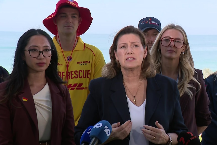 Jackie Jarvis delivers a press conference in front of a beach 