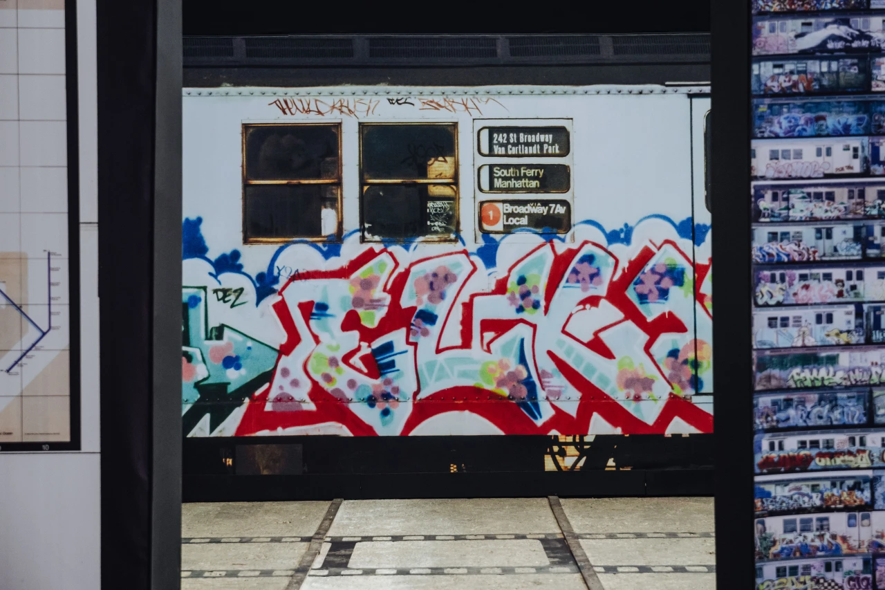 Vibrant red and multicoloured graffiti covers the lower half of a storefront with black windows and signage above in an urban setting