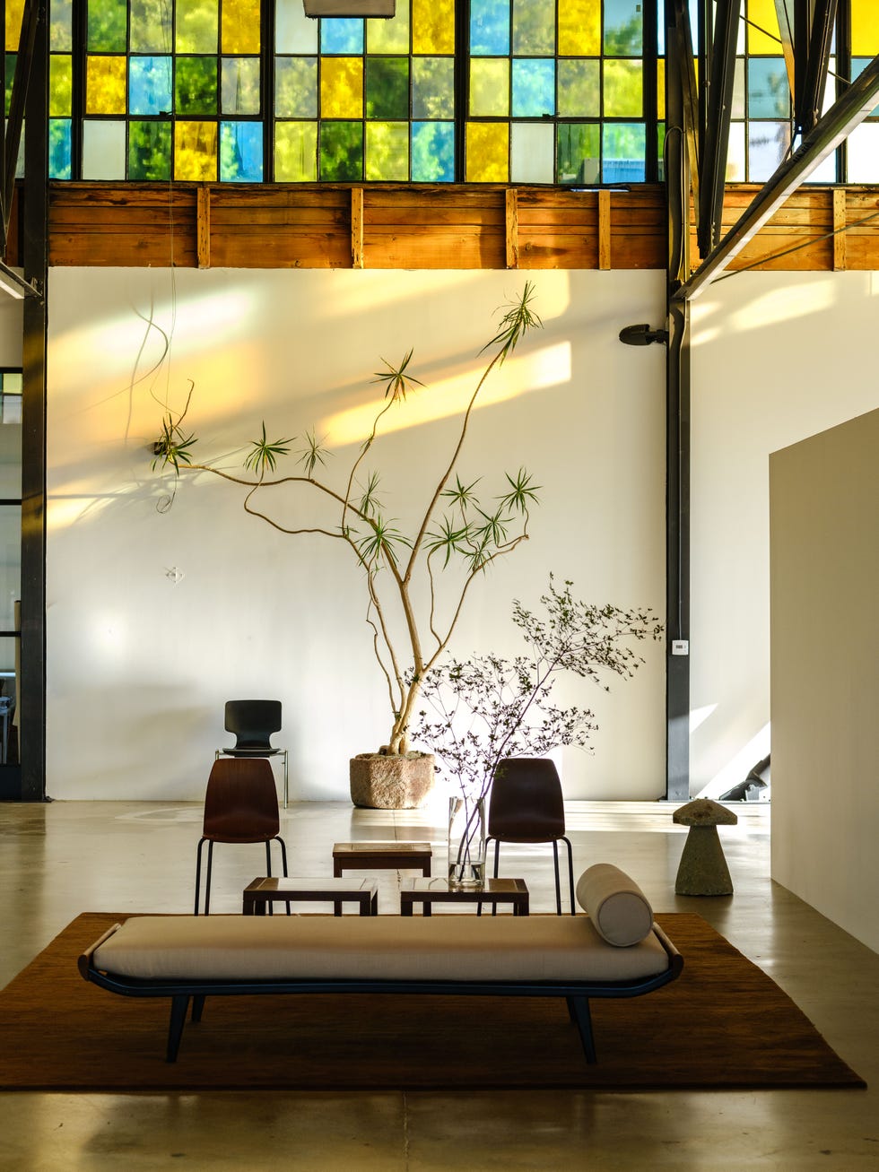 Interior space featuring a minimalist design with a sofa, plants, and colorful stained glass windows.