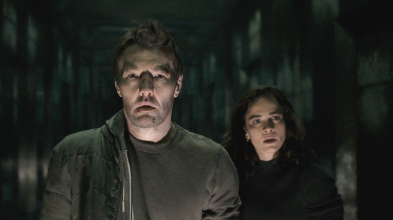 Joel Edgerton as Jason Dessen standing in a darkened hallway next to Alice Braga as Amanda Lucas in Dark Matter
