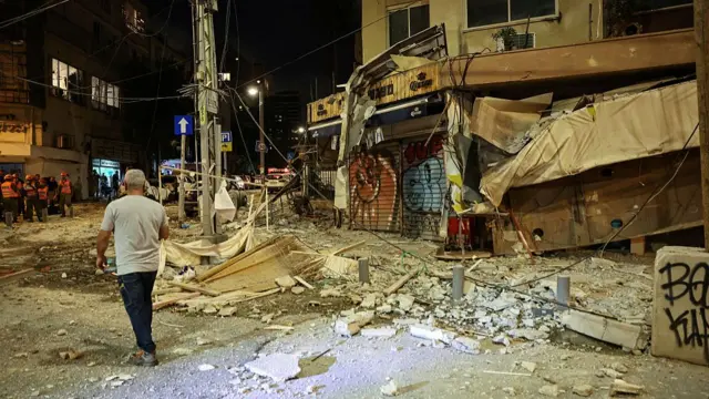 A man walks past a damaged bar in Tel Aviv. It is night time