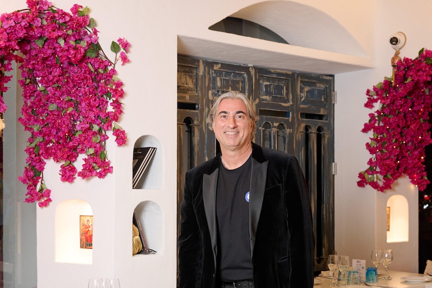 Man in suit smiles inside his restaurant