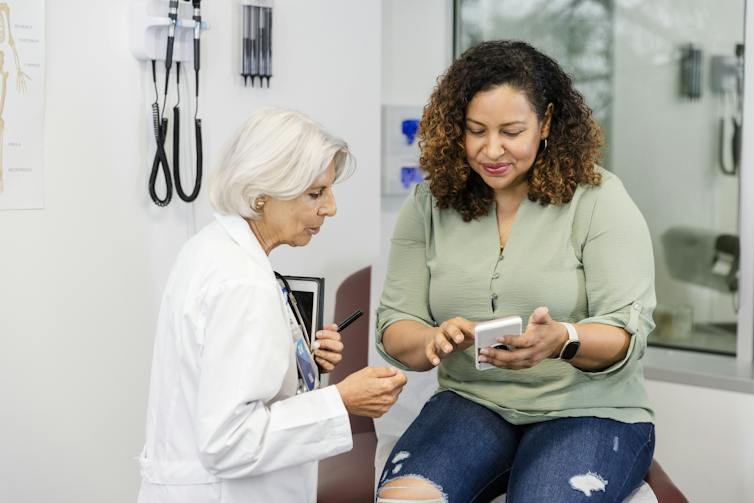 woman looking at phone with her doctor