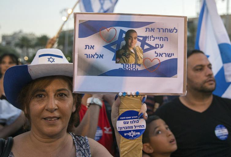 A woman holds a banner showing a man's face.