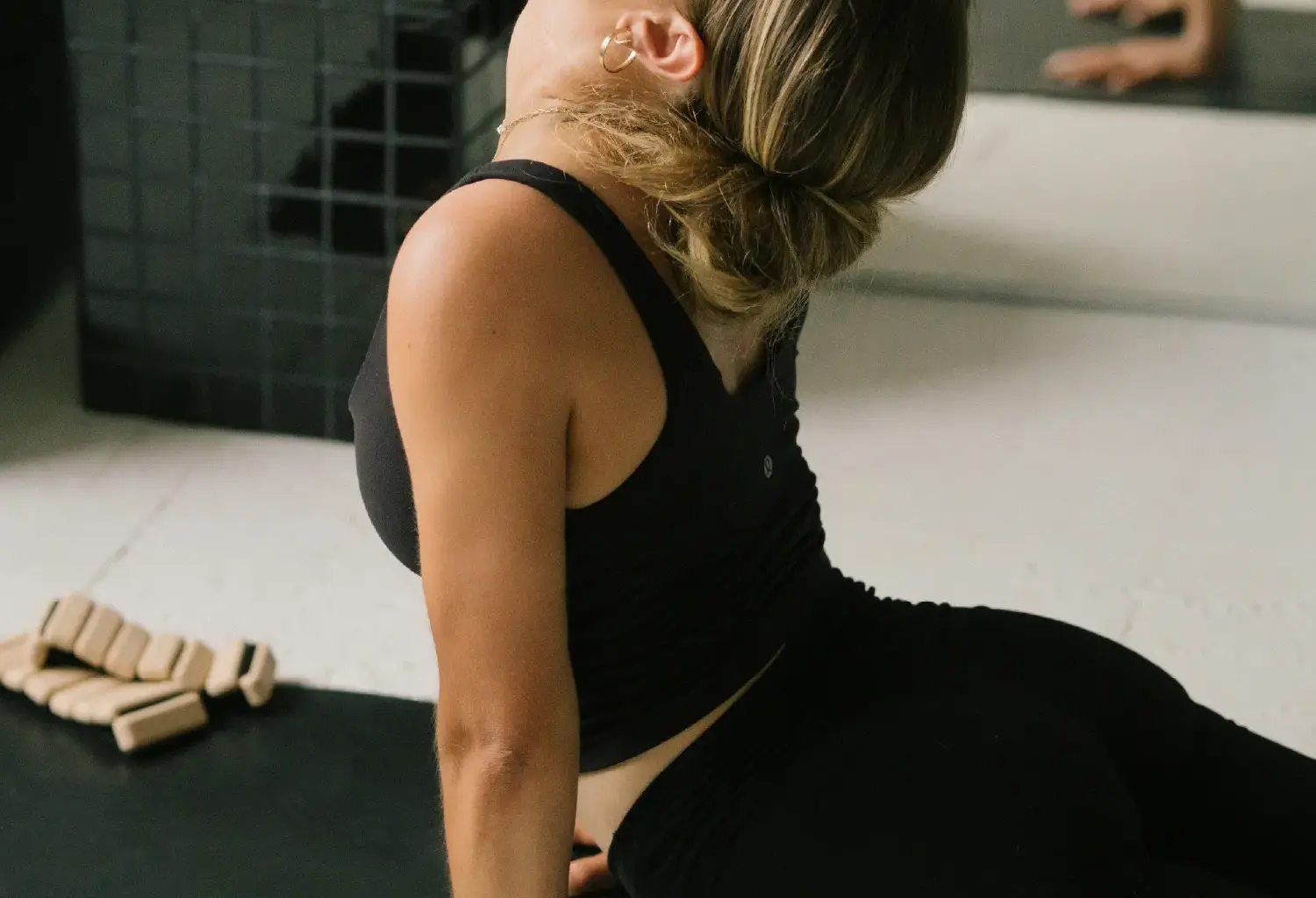 Woman practising a seated backbend stretch on an exercise mat in a fitness studio