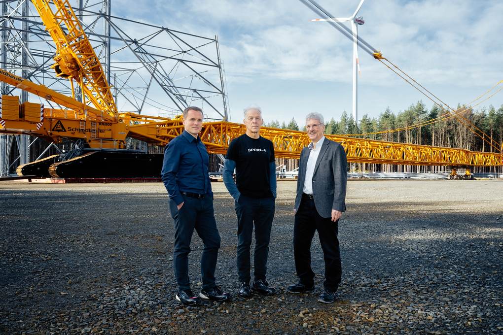Frank Adam, Martin Chaumet and Jochen Großmann standing in front of the high-altitude wind tower under construction in Schipkau