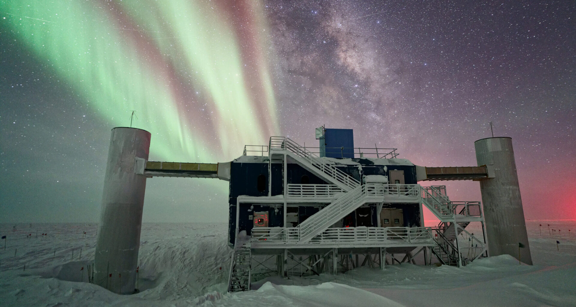 an icebound building in the dark night of the Antarctic, with stars and an aurora in the background