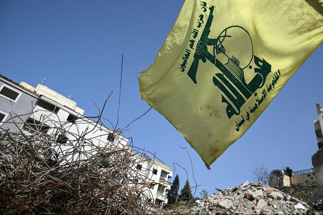 A flag of the Lebanese Shiite movement Hezbollah flutters above the rubble of a building that was hit in January by an Israeli strike in the southern Lebanese village of Qannarit, Feb. 16, 2026. (AFP Photo)