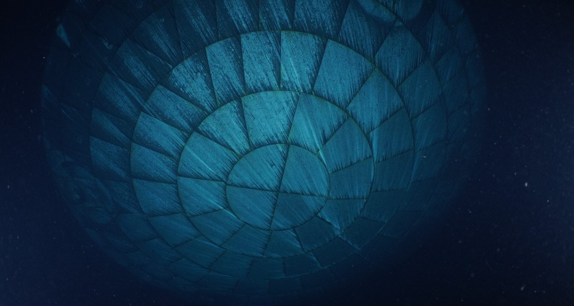 The Orion spacecraft's heat shield dominates this underwater photo. Due to the water, the heat shield appears to be teal-colored.